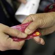 A Syrian refugee presents a World Food Programme debit card to a cashier in a Beirut shop on June 14, 2017
