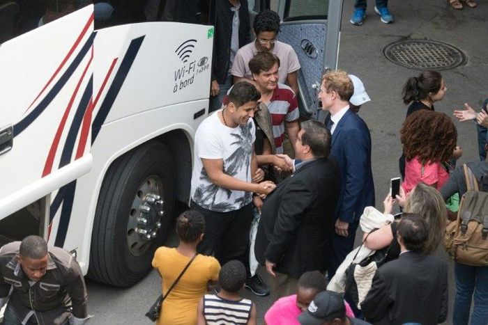 Montreal Mayor Denis Coderre greets a busload of Haitian asylum seekers from the United States as it arrives at the Olympic Stadium in Montreal on August 3, 2017