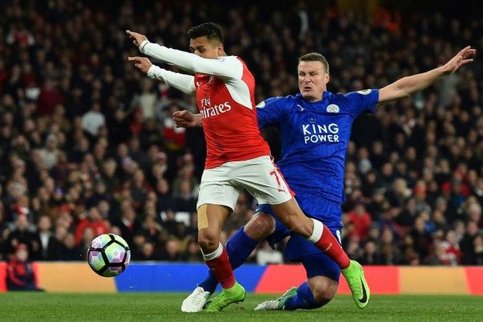 Leicester City defender Robert Huth (R) tackles Arsenal striker Alexis Sanchez during an English Premier League at the Emirates Stadium in London on April 26, 2017
