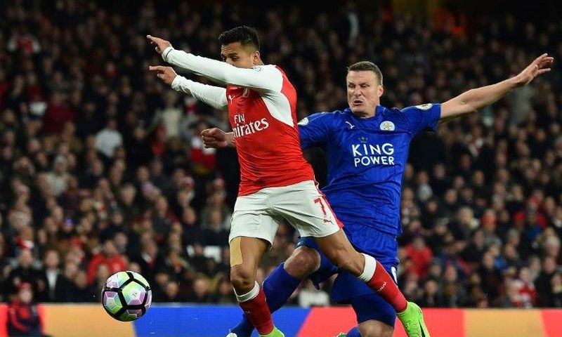 Leicester City defender Robert Huth (R) tackles Arsenal striker Alexis Sanchez during an English Premier League at the Emirates Stadium in London on April 26, 2017