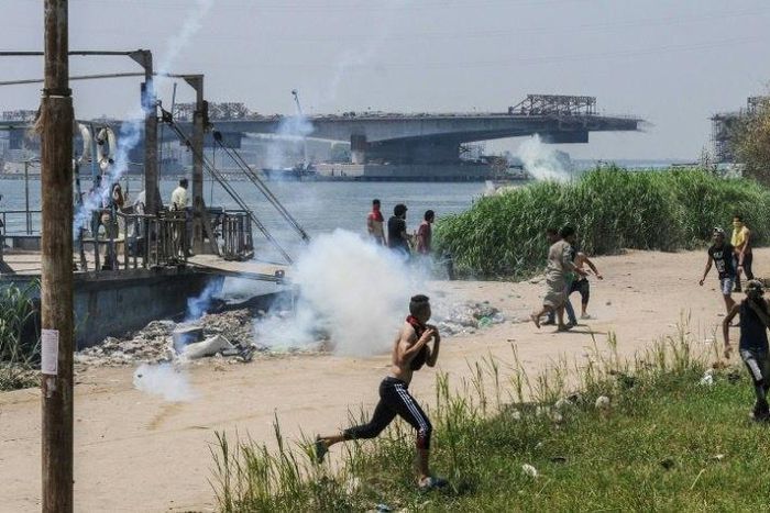 Egyptians run for cover from tear gas during clashes with security forces in the Nile island of Warraq in Giza province, north of the capital Cairo, on July 16, 2017