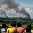 People watch as smoke rises from houses after Philippine air force planes bombed Islamist militant positions in the city of Marawi on the southern island of Mindanao