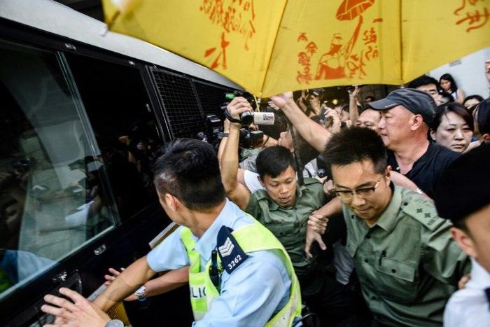 Police and supporters surround a prison van transporting Joshua Wong after his sentencing