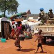 A woman and a child walk past UN peacekeepers from Gabon patrolling the Central African Republic town of Bria on June 12, 2017