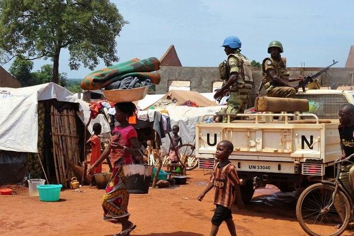 A woman and a child walk past UN peacekeepers from Gabon patrolling the Central African Republic town of Bria on June 12, 2017