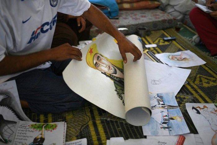 Syrian farmer Faysal shows his paintings at the Ain Issa camp in northern Syria on July 16, 2017