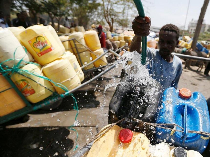 A man pours water into barrels for sale