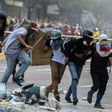 An injured Venezuelan anti-government demonstrator (2nd from right) is assisted by fellow activists during an attack at the Supreme Court -- the latest protest against President Nicolas Maduro in Caracas