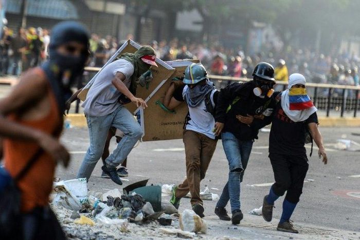 An injured Venezuelan anti-government demonstrator (2nd from right) is assisted by fellow activists during an attack at the Supreme Court -- the latest protest against President Nicolas Maduro in Caracas