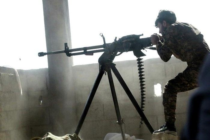 A fighter of the US-backed Syrian Democratic Forces fires a machine gun during their advance into the Islamic State group stronghold of Raqa on June 21, 2017