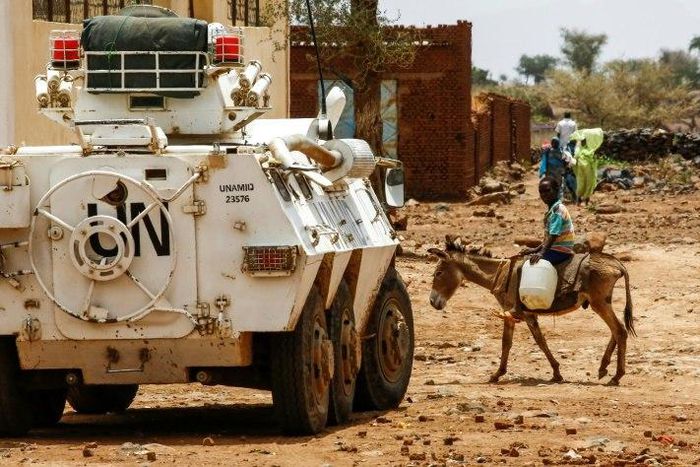 A Sudanese boy rides a donkey past an armoured vehicle of a UN-African Union mission in the war-torn town of Golo in central Darfur on June 19, 2017