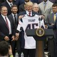 US President Donald Trump holds a jersey given to him by New England Patriots owner Robert Kraft (R) and head coach Bill Belichick (L) alongside members of the team during a ceremony at the White House in April 2017