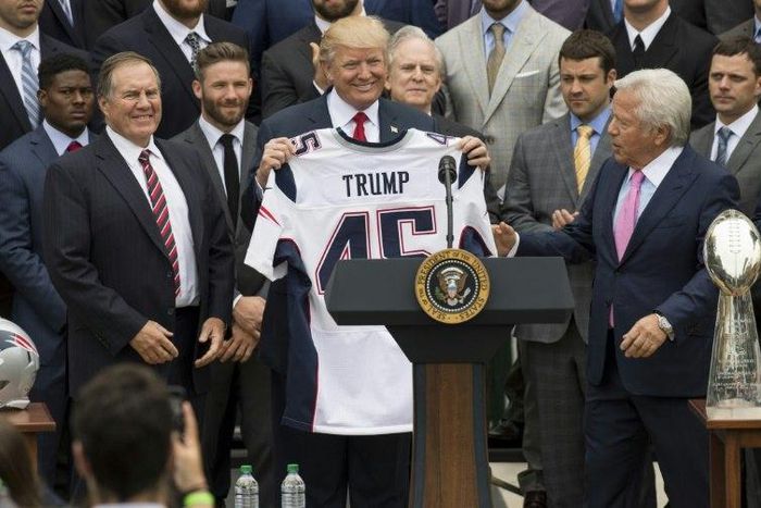 US President Donald Trump holds a jersey given to him by New England Patriots owner Robert Kraft (R) and head coach Bill Belichick (L) alongside members of the team during a ceremony at the White House in April 2017