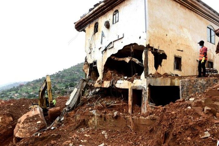 An excavator clears mud and debris after the partial collapse of a hillside in Freetown, Sierra Leone, that swept away hundreds of homes