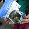 A man shows two envelopes containing marijuana he just purchased at a pharmacy in Montevideo, on July 19, 2017