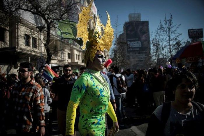 Carrying rainbow flags and banners, participants in Santiago's Gay Pride Parade, some dressed in drag, marched through the city's streets on July 1, 2017