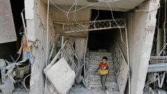 A Syrian child walks out of damaged building following an air strike on the rebel-held town of Arbin, east of the capital, on July 22.