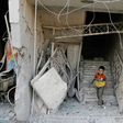 A Syrian child walks out of damaged building following an air strike on the rebel-held town of Arbin, east of the capital, on July 22.