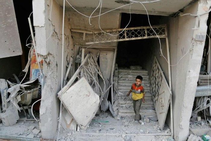 A Syrian child walks out of damaged building following an air strike on the rebel-held town of Arbin, east of the capital, on July 22.