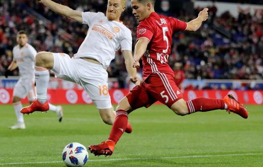 Connor Lade (R) of New York Red Bulls takes a shot as Jeff Larentowicz of Atlanta United defends in the first half during the Eastern Conference Finals Leg 2 match, at Red Bull Arena in Harrison, New Jersey, on November 29, 2018