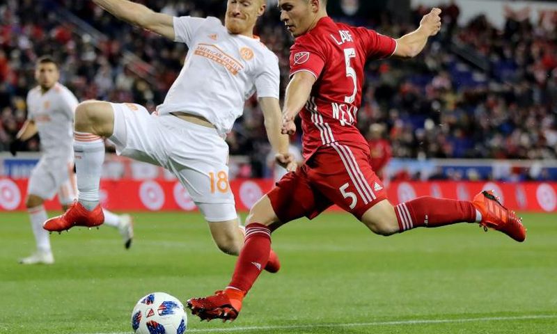Connor Lade (R) of New York Red Bulls takes a shot as Jeff Larentowicz of Atlanta United defends in the first half during the Eastern Conference Finals Leg 2 match, at Red Bull Arena in Harrison, New Jersey, on November 29, 2018