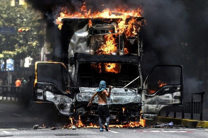 A truck set ablaze by opposition activists blocks an avenue during a protest in Caracas