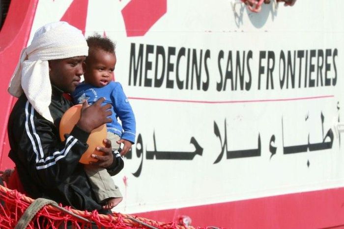 A migrant man carries a child as they disembark from the Italian rescue ship Vos Prudence run by NGO Medecins Sans Frontieres (MSF) as it arrives in the early morning of July 14, 2017, in the port of Salerno carrying 935 migrants, including 16 children...