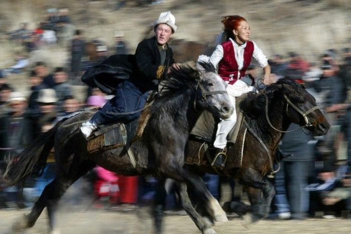 A Kyrgyz man rides to catch a woman wearing a traditional bridal gown during a folk festival