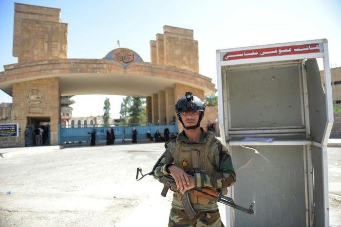 An Iraqi soldier stands guard outside the University of Mosul as students arrive to take their exams
