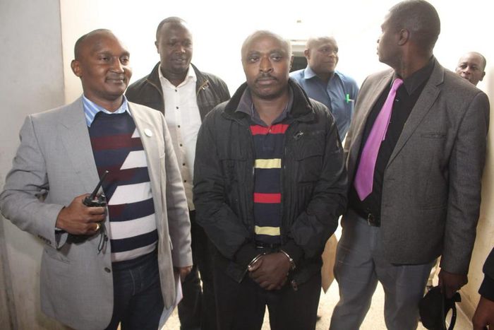 Mugo wa Wairimu escorted by police officers during his court appearance