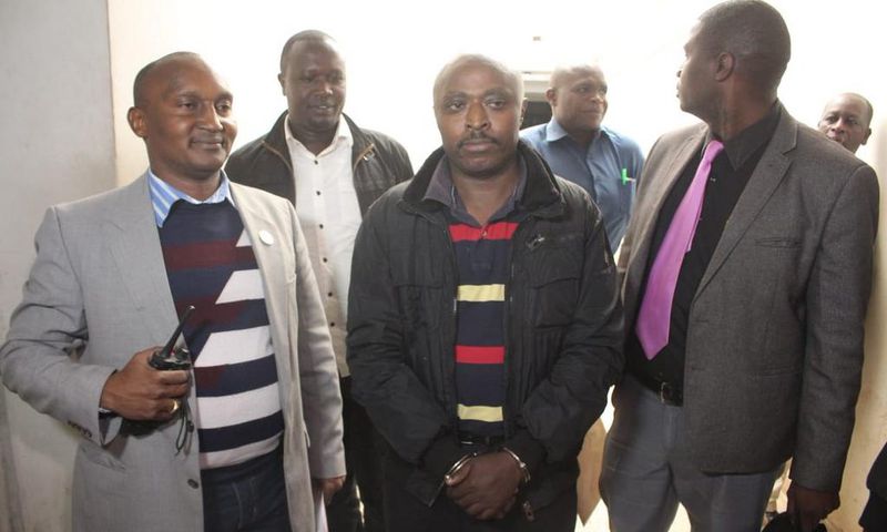 Mugo wa Wairimu escorted by police officers during his court appearance