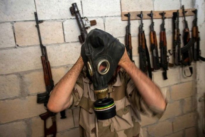 A rebel tries on a gas mask seized from a Syrian army factory in the north-western province of Idlib