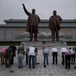Tourists bow before statues of late North Korean leaders Kim Il-Sung (L) and Kim Jong-Il (R), on Mansu hill