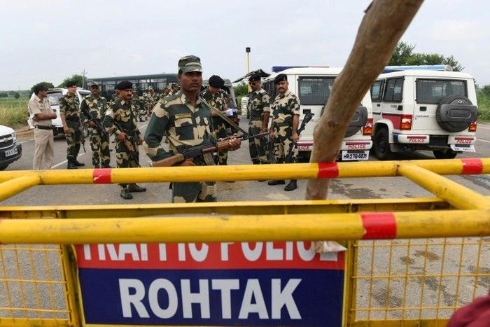 Indian security personnel stand guard along a road near Sonariya jail in Rohtak