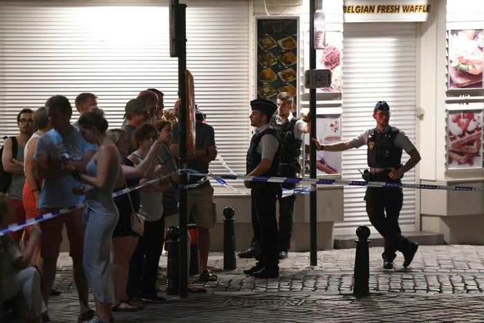 Police officials stand alert as members of the public gather behind a cordon on a street outside Gare Centrale in Brussels, on June 20, 2017