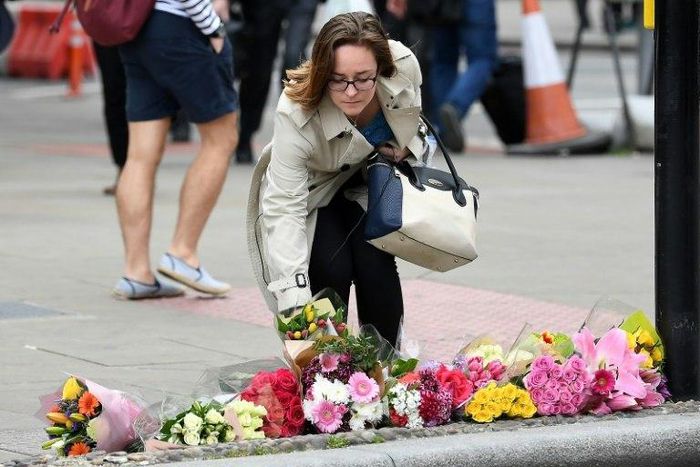 A woman lays a bouquet of flowers at a pedestrian crossing by Borough market following attacks which left eight people dead