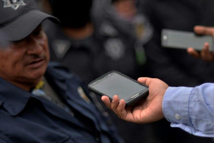 A Mexican journalist interviews a police officer during a protest rally in Chilpancingo, Guerrero state