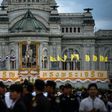 People gather before giving alms to Buddhist monks in front of a photograph of Thai King Maha Vajiralongkorn at the Royal Plaza in Bangkok on July 28, 2017