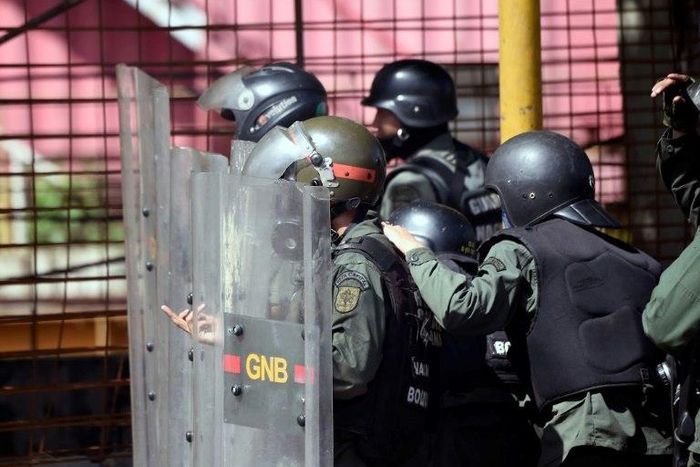 Venezuelan national guard officers in riot gear protect themselves during Friday's protest against President Nicolas Maduro's government