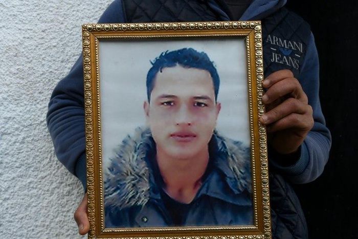 Walid Amri, brother of alleged Berlin Christmas market attacker Anis Amri, holds a portrait of his brother outside the family house in Oueslatia on December 23, 2016