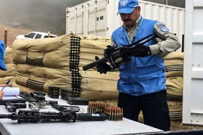 Handout picture released by the United Nations showing a member of the UN international observers' mission in Colombia holding a weapon surrendered by the Revolutionary Armed Forces of Colombia (FARC) as part of the peace process