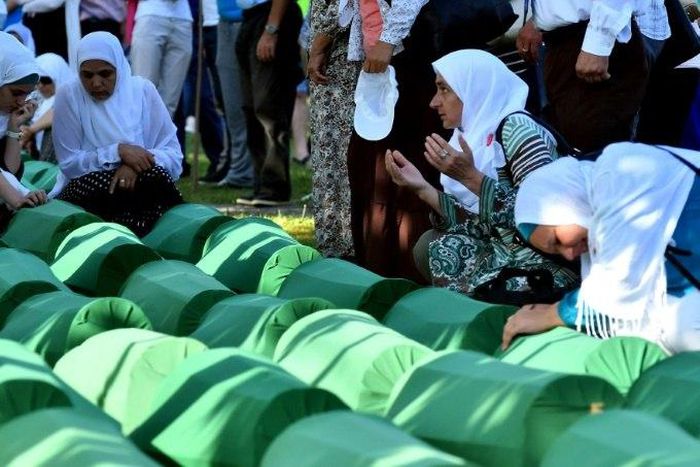 Bosnian women offers prayers near the caskets of 71 victims of the 1995 Srebrenica massacre, at the memorial cemetery in the village of Potocari on July 11, 2017