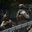 Afghan security forces stand guard at the site of a suicide blast near Iraq's embassy in Kabul