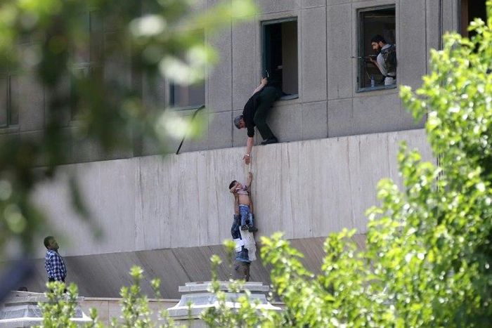 Iranian policemen evacuate a child from the parliament building in Tehran on June 7, 2017 during an attack on the complex