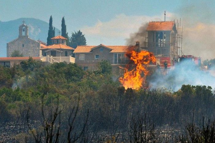 A forest fire consumes vegetation next to a monastery on the Lustica peninsula near the town of Tivat, Montenegro, on July 17, 2017