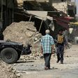 A man walks past a member of the Iraqi forces in west Mosul a few days after the city's recapture from Islamic State fighters