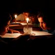 A picture taken on June 13, 2017 shows Palestinian children at home reading books by candle light due to electricity shortages in Gaza City