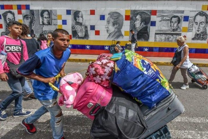 Thousands of Venezuelans, many hauling overloaded suitcases, cross the border into Colombia to escape unrest and penury at home