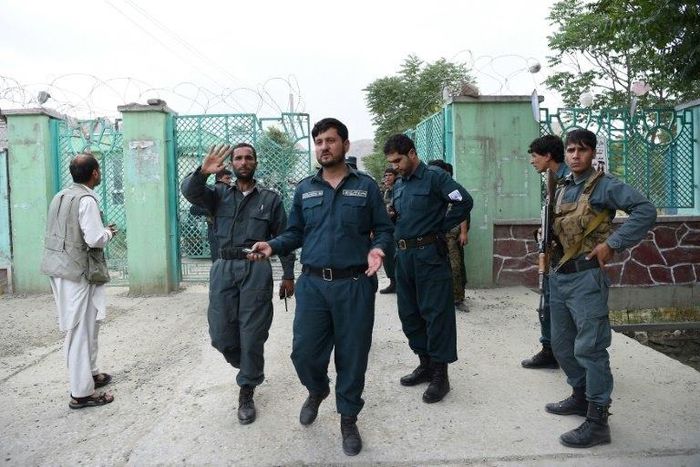 Afghan policemen stand at a gate near the site of a series of explosions that targeted a funeral in Kabul on June 3, 2017