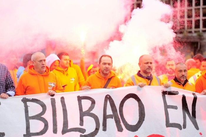 Bilbao's dockers hold a banner with flares in background during a two-day strike at the Port of Bilbao, in the Spanish Basque city of Santurtzi on June 15, 2017
